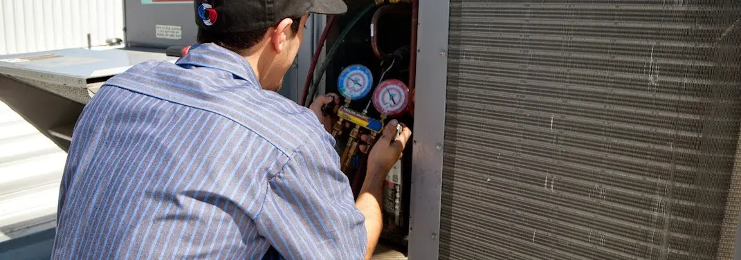 HVAC technician servicing a condenser unit in Taylor